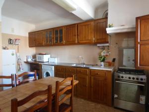 a kitchen with wooden cabinets and a table and a sink at Apartamento Rosa in Vila Nova de Milfontes