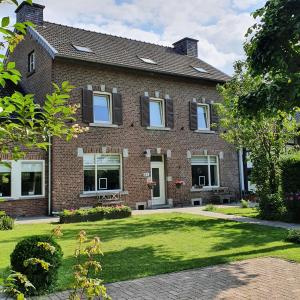 Luxe B&B Vroelen-Noorbeek في نوربيك: منزل من الطوب مع ساحة خضراء