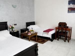 a bedroom with two beds and a table and a desk at Ayouz House Hotel in Dakhla