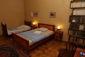 a bedroom with two beds and a book shelf at Sun Guest House in Kutaisi