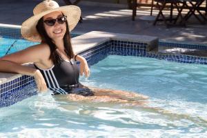 Una donna con un cappello in piscina di Pousada Aguas Claras a Búzios