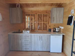 a kitchen in a wooden cabin with a sink and a refrigerator at Cyprus Glamping Park in Ayios Theodhoros