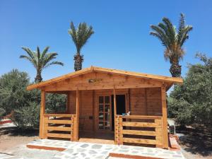 a wooden building with palm trees in the background at Cyprus Glamping Park in Ayios Theodhoros
