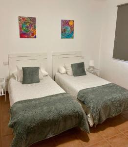two beds in a room with paintings on the wall at Apartamento los Rostros in La Santa