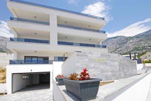 a white building with two potted plants in front of it at Sunset Apartments in Makarska