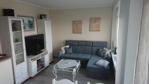 ein Wohnzimmer mit einem blauen Sofa und einem TV in der Unterkunft Traumhafte Meeresblick FeWo in Sierksdorf