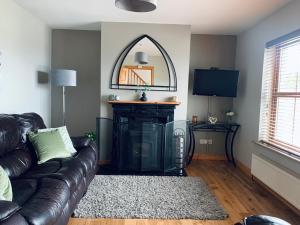 a living room with a leather couch and a fireplace at Wild Atlantic Way House in Achill