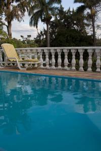 a swimming pool with a chair next to a fence at Pousada Lagoa in Belo Horizonte