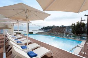 a row of chairs and umbrellas next to a swimming pool at Melina Bay Boutique Hotel in Kassiopi