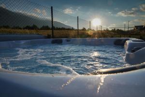 a hot tub filled with water in front of a fence at Mountain villa Aleksia- with JACUZZI in Razlog