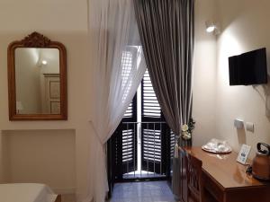 a bedroom with a mirror and a window with curtains at Estlevante B&B in Vieste