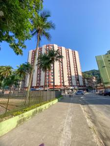 een hoog gebouw met palmbomen voor een straat bij Estúdio/Apartamento praia de São Vicente in São Vicente