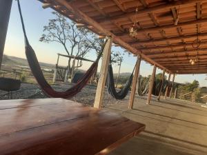 a porch with a hammock and a table at Pousada flores de ipê in Capitólio