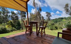 a table and two chairs on a wooden deck at Glamping Verde 360 in Guasca