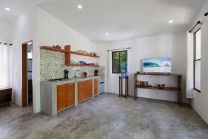 eine Küche mit weißen Wänden, Holzschränken und einem Fenster in der Unterkunft Zen Casita + Studio in Rivas