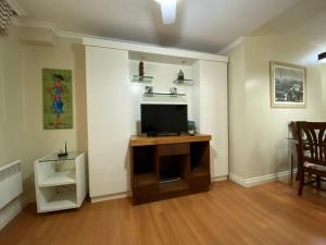 sala de estar con TV en un soporte de madera en MRG - Faça tudo a pé - 1D no Centro de Gramado, en Gramado