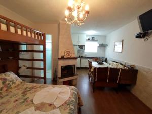 a bedroom with a bed and a table and a kitchen at Chalé dos Alpes I em Monte Verde in Monte Verde