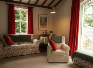 ein Wohnzimmer mit 2 Stühlen und roten Vorhängen in der Unterkunft Drumena Cottage in Kilcoo