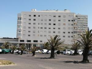 a large white building with palm trees in a parking lot at ESCAPADA a PdE !! in Punta del Este