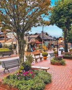 a park with benches and flowers in front of a building at Chalé dos Alpes I em Monte Verde in Monte Verde