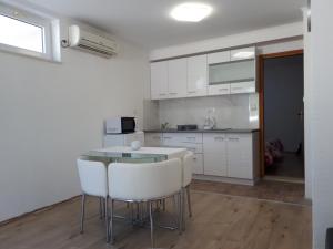 a kitchen with white cabinets and a table and chairs at Sweet Apartment Ines in Mlini