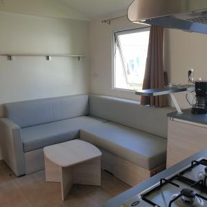 een woonkamer met een bank en een raam bij Mobil home 2020 3ch + clim , équipé 4* , vendée in Talmont