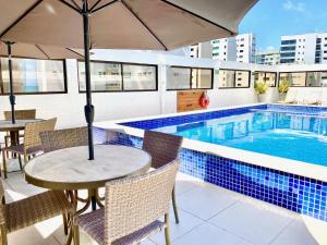 uma mesa com um guarda-sol ao lado de uma piscina em Kastel Manibu Recife - Boa Viagem em Recife