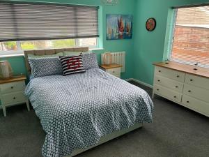 a bedroom with a bed and blue walls and windows at Seagull’s View in Lytham St Annes
