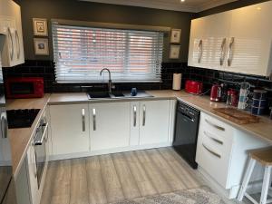 a kitchen with white cabinets and a sink and a window at Seagull’s View in Lytham St Annes