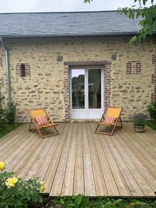 2 sillas en una terraza de madera frente a una casa en Gite du golfe, en Gonneville-sur-Mer