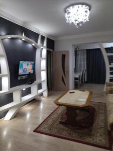 a living room with a table and a tv on a wall at Apartment for you in Tbilisi City