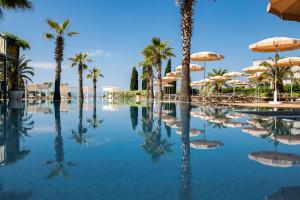 a swimming pool with palm trees and umbrellas at Radisson Blu Resort & Spa in Split