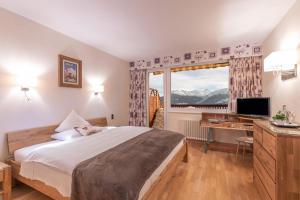 una camera da letto con un letto, una scrivania e una finestra di Hotel Ad'Eldorado a Crans-Montana