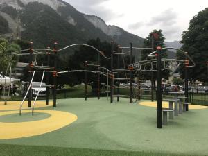 un parque infantil en un parque con montañas al fondo en Les Tilleuls, en Le Bourg-dʼOisans