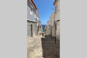a street in a town with buildings and the ocean at Sesimbra Concept in Sesimbra