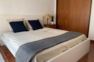 a white bed with two blue pillows on it at Sesimbra Concept in Sesimbra