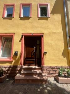 a yellow building with stairs leading to a door at Main-Apartments in Wertheim