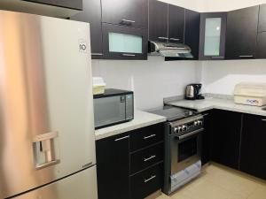 a kitchen with black cabinets and a white refrigerator at LA CASA BLANCA in Lunahuaná