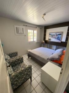um quarto com uma cama e uma cadeira em Casa em condomínio à beira mar de Porto de Galinhas em Ipojuca