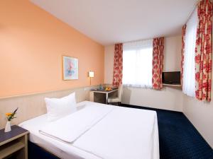 a hotel room with a white bed and a window at ACHAT Hotel Leipzig Messe in Leipzig