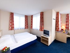 a hotel room with a bed and a television at ACHAT Hotel Leipzig Messe in Leipzig +41 photos