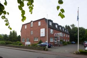 a red brick building with a car parked in front at Hotel an der Schlei Garni in Fahrdorf