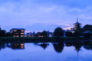 a view of a lake with a pagoda in the background at MIROKU NARA by THE SHARE HOTELS in Nara