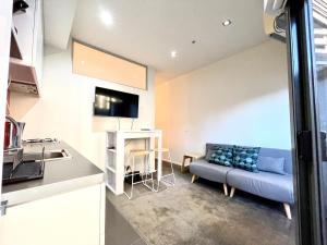 ein Wohnzimmer mit einer blauen Couch in einer Küche in der Unterkunft ReadySet Apartments at Kett in Melbourne