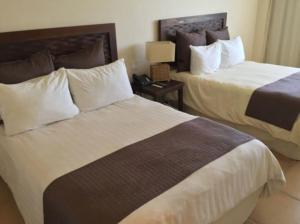 Habitación de hotel con 2 camas y mesita de noche en Private family room in Coronado Luxury Club & Suites, en Playa Coronado