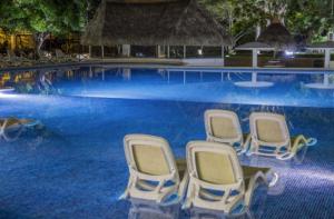 a row of chairs in a swimming pool at a resort at Private family room in Coronado Luxury Club & Suites in Playa Coronado