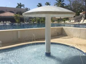 a umbrella in the middle of a pool with water at Private family room in Coronado Luxury Club & Suites in Playa Coronado