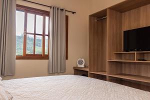 a bedroom with a bed and a flat screen tv at Pousada Recanto da Serra in São Pedro da Serra +180 photos