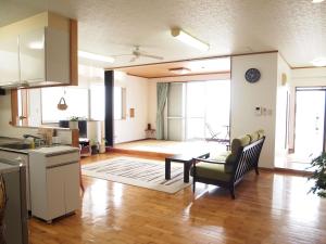 eine Küche und ein Wohnzimmer mit einem Sofa und einem Stuhl in der Unterkunft Rental Villa Luana Waioli in Tomigusuku