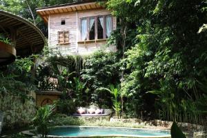a house with a garden with a swimming pool at Roots Tree House in Uluwatu